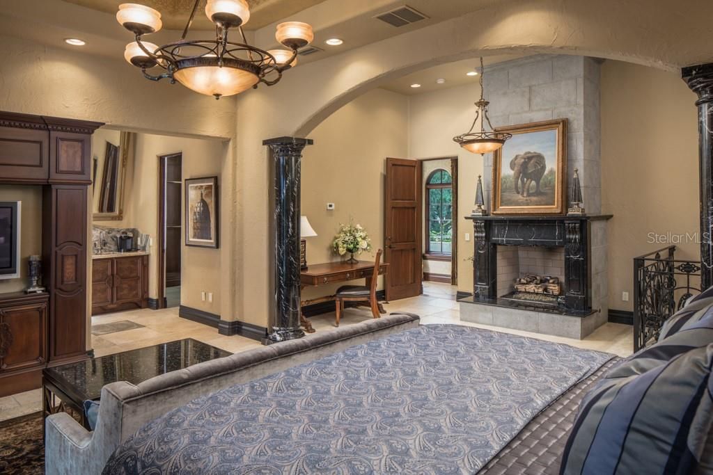 This master suite offers a gas fireplace adorned in dark onyx and a wrought iron, spiral staircase leading to the formal office on the first floor.