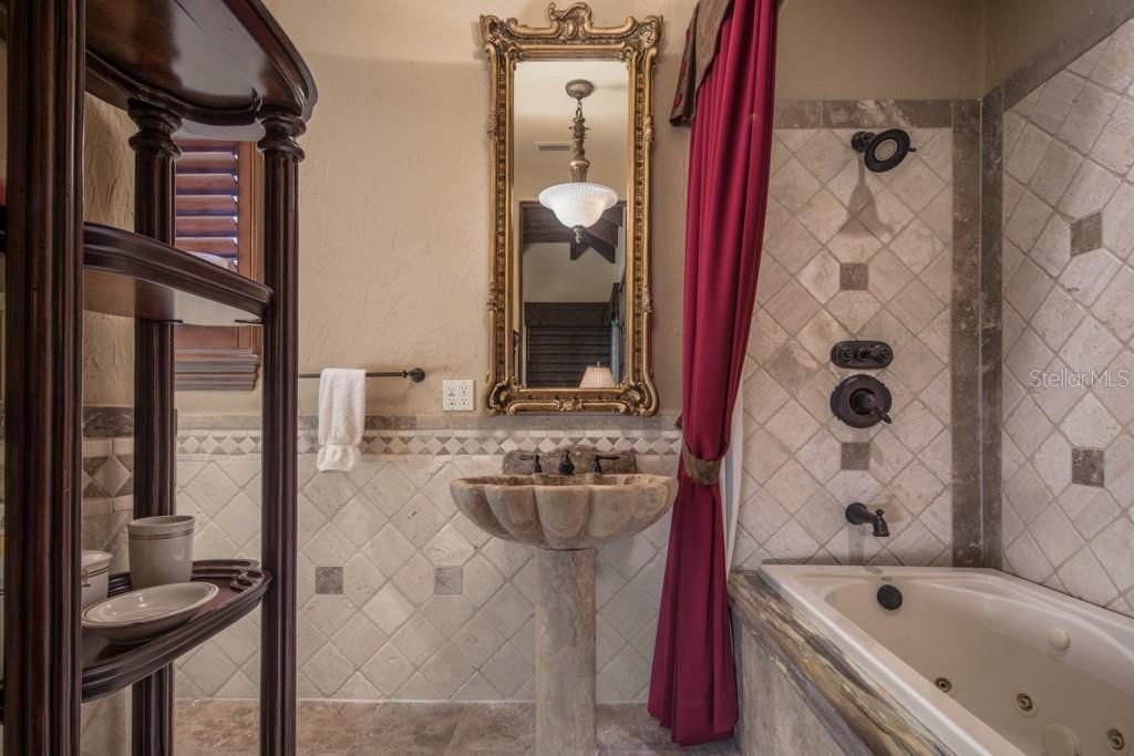 The guest cabana bath features an onyx and tile spa tub with shower.