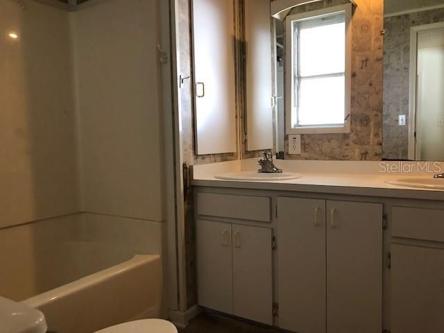 Tub shower combo with double sinks in bathroom.