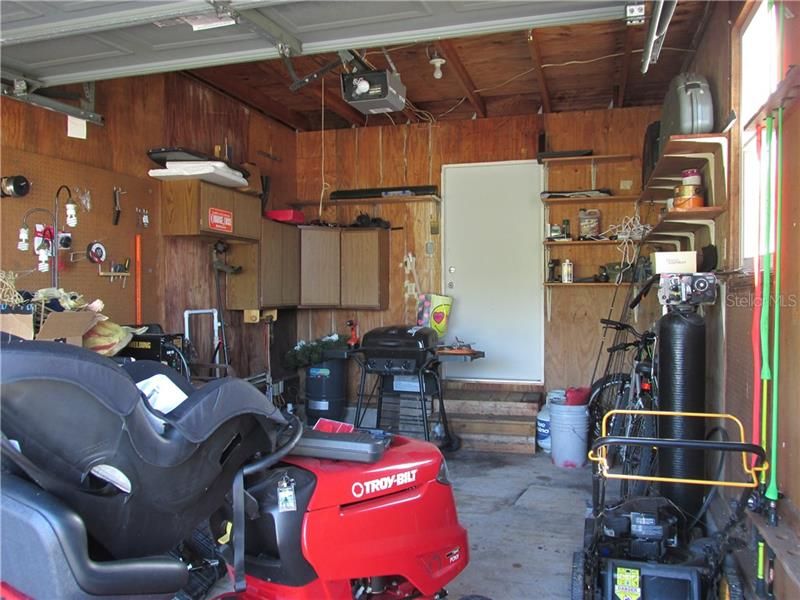 Garage has workbench, cabinets and shelves.