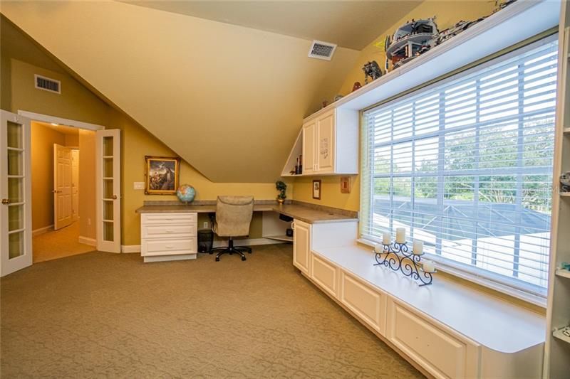 Opposite view of Bonus Room, showing hallway, built in desk, bookcases and view to the rear of the property.