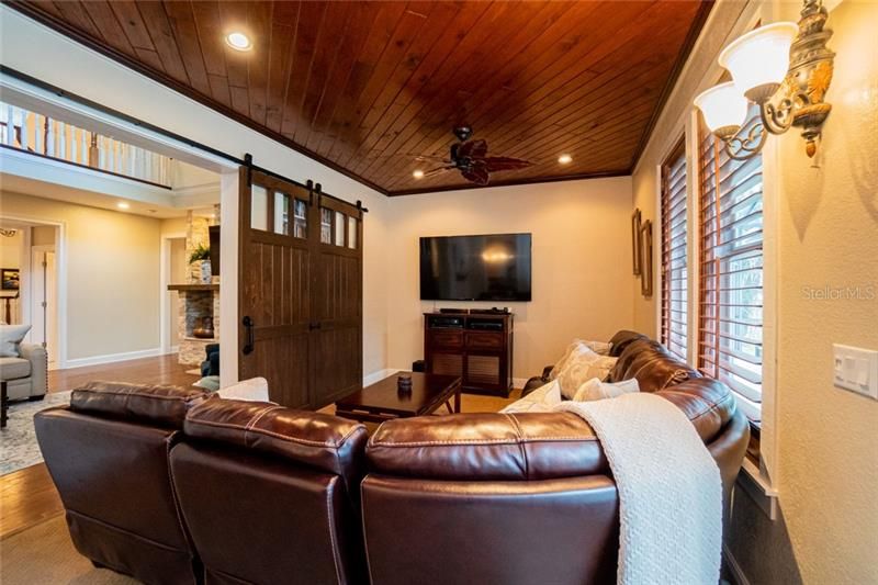 Family room with wood ceiling and exposed siding in nook.