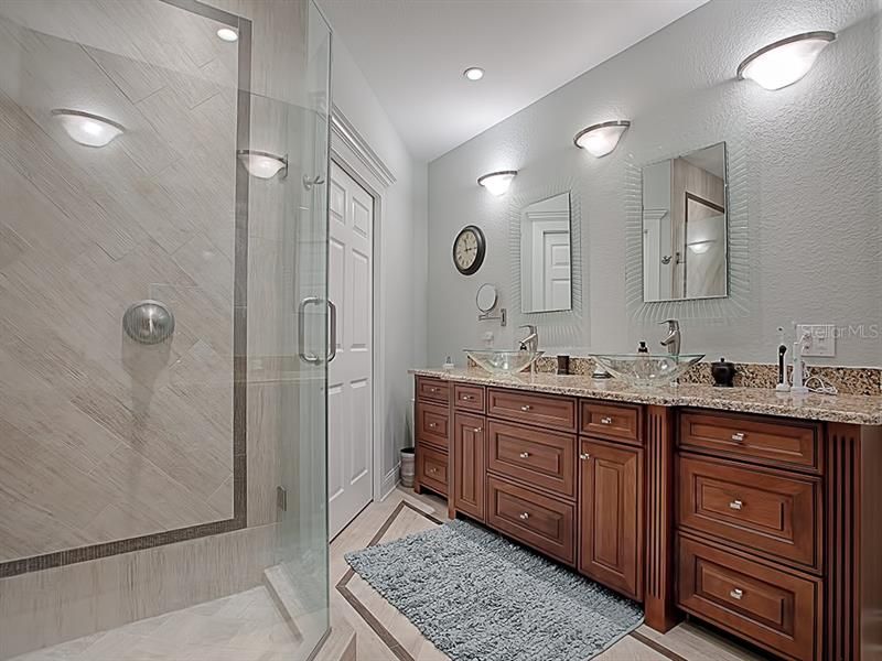 Beautiful dual vanity with upgraded fixtures and plenty of storage! More closet space can be found through the doorway.
