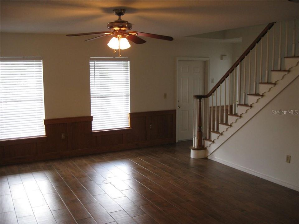 First Floor Dining Room showing stairs to upstairs has ceiling fan and wood look ceramic tile floor.