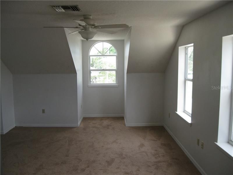 Another view of Bedroom #3 Upstairs which has ceiling fan and carpet.