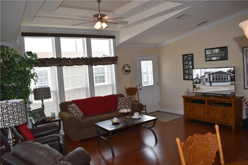Living Room w/view of the entrance door, engineered hardwood floors and tray ceiling.