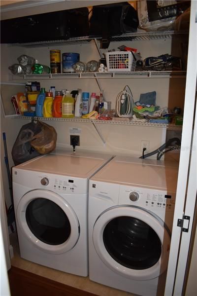 Laundry closet with front load washer and dryer and shelving.