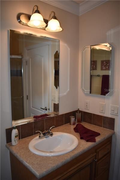 Master bathroom sink w/tile back splash, mirrored storage cabinet and crown molding.