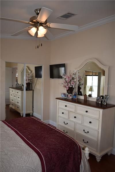 Master bedroom w/ceiling fan, engineered hardwood floors, TV mount and crown molding.