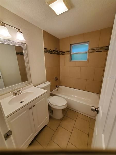Guest bathroom with new vanity, new tile shower, new toilet, new tile floor, new vent fan, new lighting