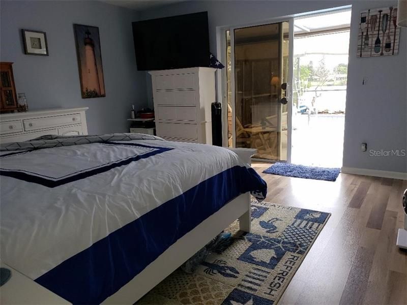 Master bedroom with bed  facing the sliding door to the pool and overlooking the lake