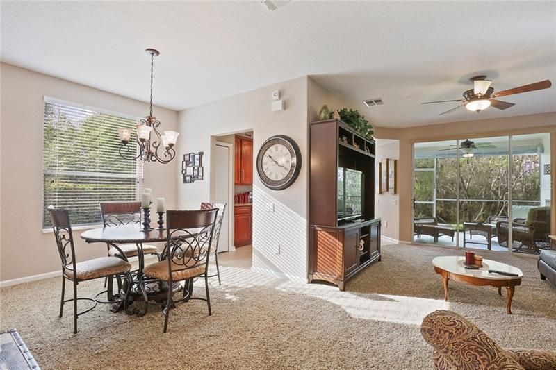 Dining room and living room with view of the covered screened lanai. Lanai has wood tile flooring and faces the greenbelt