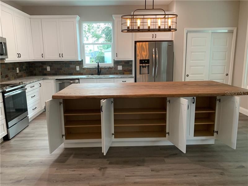 Huge center island with tons of storage on both sides. All cabinets and draws are soft self closing. Solid wood live edge counter top.
