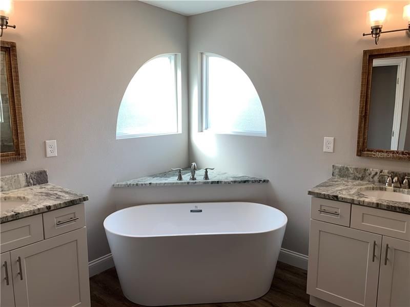 Modern soaking tub with all new cabinetry and granite counters.