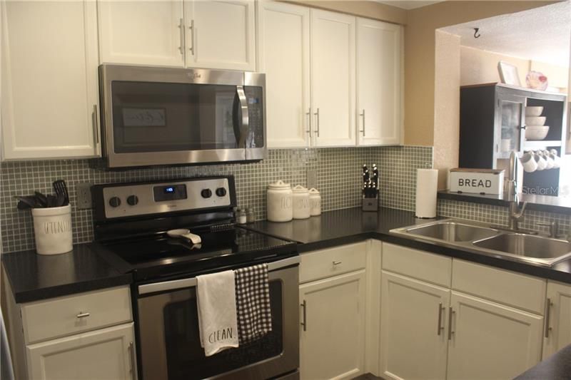 Remodeled Kitchen.  New Appliances, New Flooring, New Hardware on Painted Wood Cabinets, New Counter Tops, New Kitchen Faucet, New Back Splash and Undermount Lighting.   Pass through to Dining Room.
