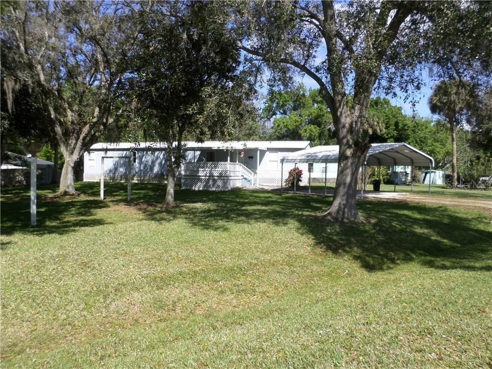 FRONT WITH LOTS OF TREES & CARPORT