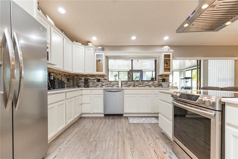 Kitchen featuring White wood cabinetry, stainless steel appliances, quartz counters and recessed lighting.