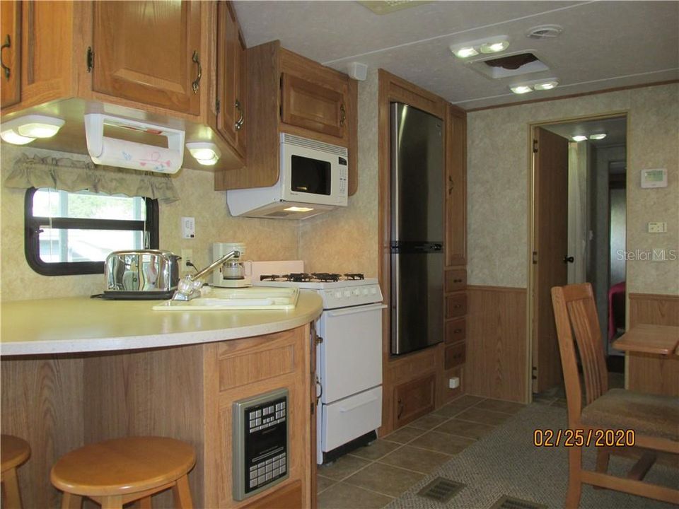 Kitchen has wood cabinets; appliances include a gas stove, newer refrigerator and microwave.