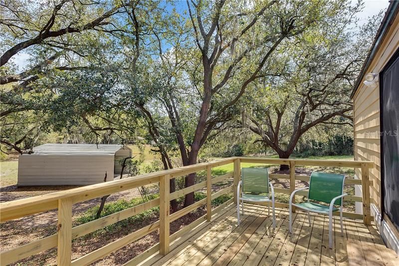 DECK IS SURROUNDED BY OAK TREES FOR SHADE