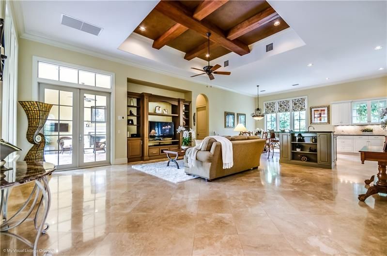 Beautiful travertine floors, beamed ceiling and built-ins in the Family Room with French Doors to the covered Lanai
