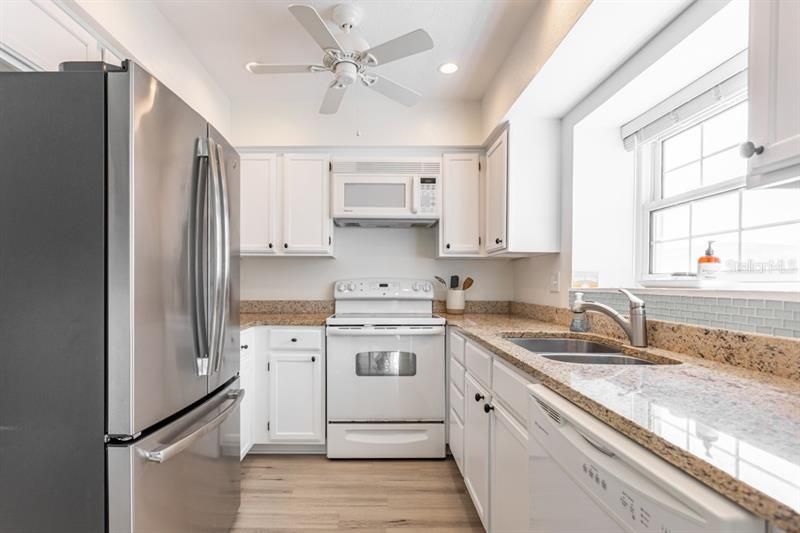 The kitchen features white cabinetry, granite countertops, stainless steel refrigerator.