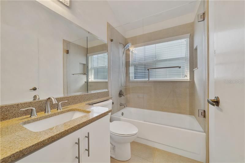 FULLY UPDATED GUEST BATH also boasts quartz counters and a frameless glass tub/shower!