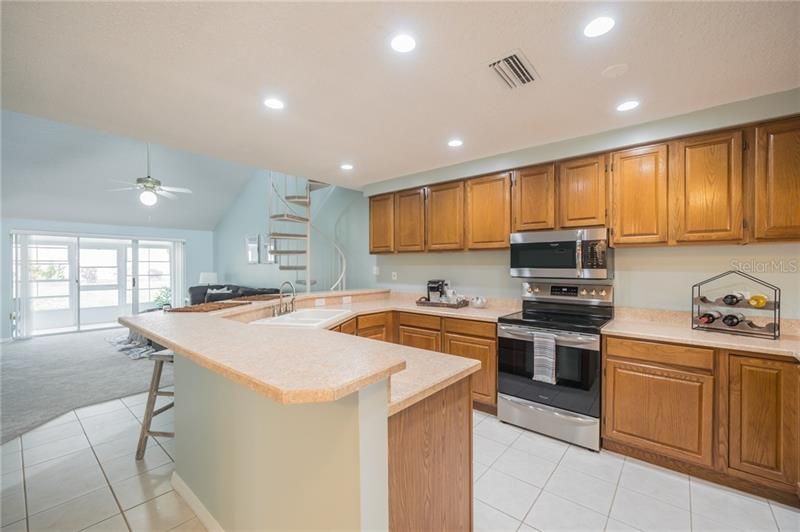 Kitchen with wrap around breakfast/lunch bar open to family room and sliders to rear enclosed porch