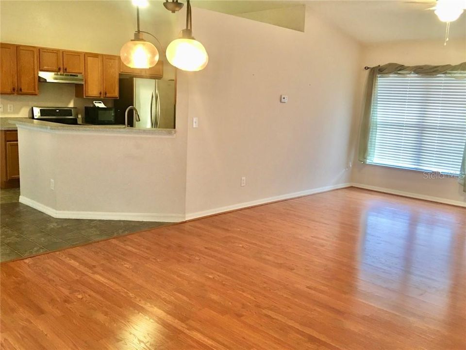 Great room with updated laminate flooring, vaulted ceiling, nice lighting and draperies.