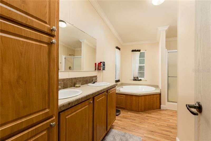 Master bath has dual vanities, a tub and a shower