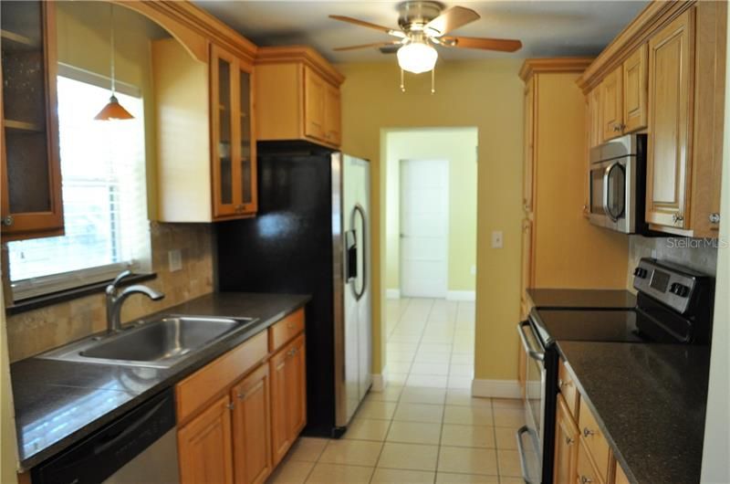 Galley kitchen with Stainless Steel Appliances, granite counter top and tile floor