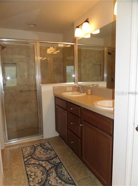Master Bath with Dual vanity sink, vinyl flooring, private commode and walk-in shower with a bench.
