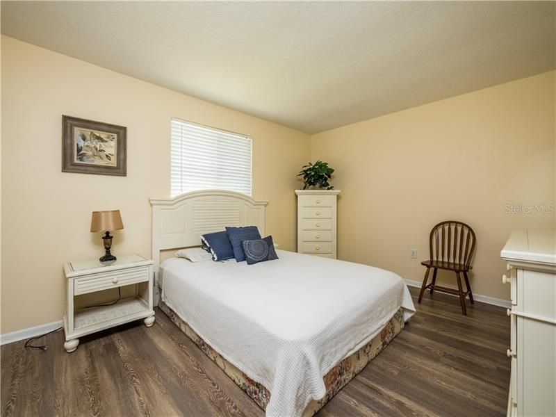 GUEST BEDROOM WITH FLOORING THAT MATCHES THE REST OF THE HOME.