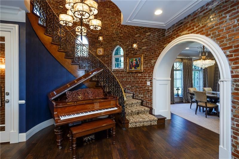 Dramatic staircase -brick walls - arched entry into formal Dining Area