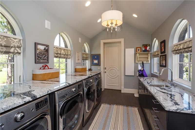 Large lakefront Laundry Room with 2 washers and 2 dryers and marble counter tops with storage below