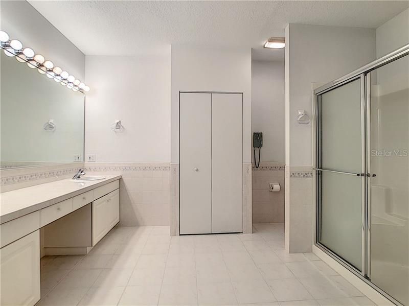 Master bathroom with linen closet, privacy commode area and shower. Tile flooring.