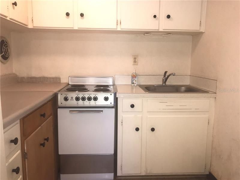 The stove is spic and span and there is an abundance of cabinets in the kitchen area.