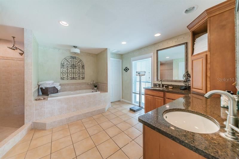 Master bathroom with exquisite cabinets and double sink vanities, walk in shower and jetted tub and door leading to the walk in closet.