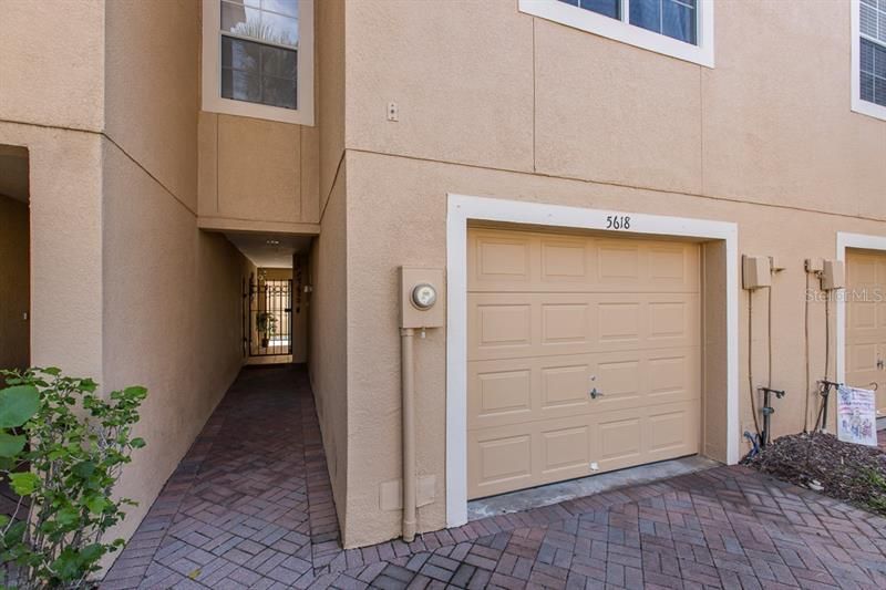 Brick walk way gated access to Covered court yard with access to elevator, home stairs, storage and private garden patio.