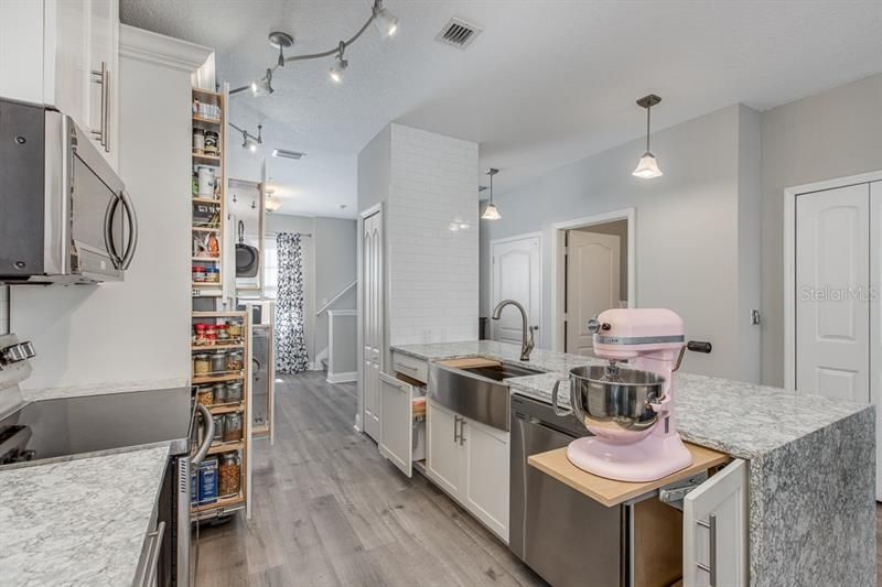 View of some of the custom built ins.. Stand mixer lift, dual space trash cabinet, 2 tiered spice/storage rack. 2 tiered pan rack. To the far right is an additional storage closet unique to this home.