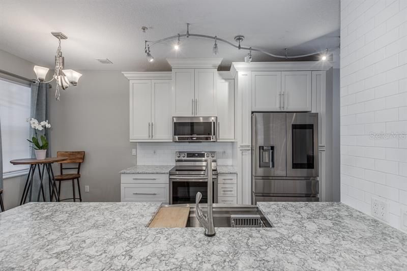 Hand crafted custom kitchen, smart refrigerator, lights can change on command with Alexa for a variety of colors and moods.. touch less faucet, custom sliding cutting board and dish rack. Quartz counters, subway tile.