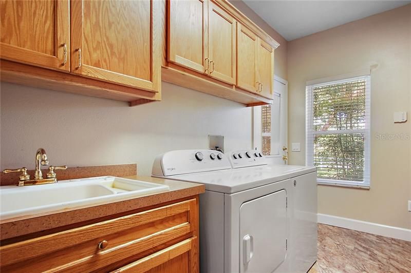 Laundry room with custom cabinetry, washer, dryer, utility sink and built in ironing station