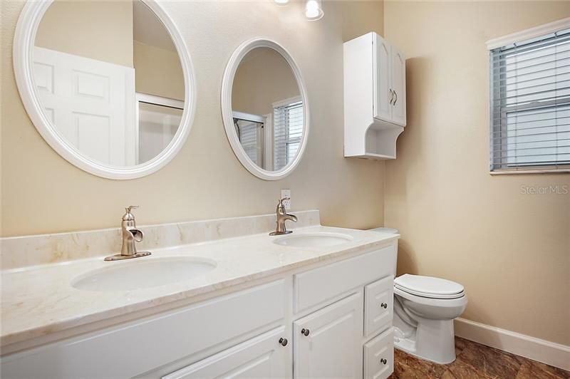 Shared bathroom for the two bedrooms with dual vanity sinks, linen closet and tub/shower