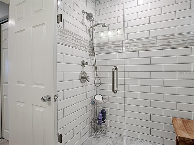 Floor to ceiling tile and a a frameless shower door in the guest bath