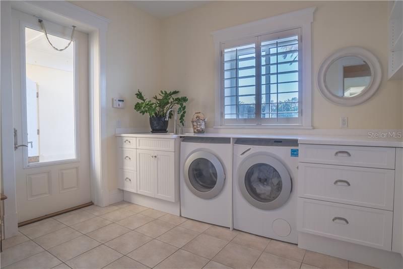 Oversized laundry room with built in cabinets, large solid surface folding counter and sink.  Built in cubbies not shown.  Exit to the outside to the garage (detached), covered entry.
