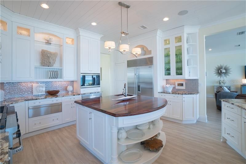 Kitchen boasts coastal elegance with detailed tongue and groove wood ceilings, specialty island counter made of Goncalo Alves wood aka (Tigerwood).46inch cabinets with lighted detail, chef grade appliances full walk in pantry (not shown) open concept to the family room and breakfast room