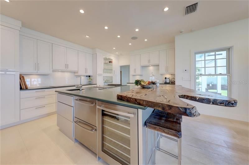Dramatic modern design meets European elegance in this kitchen fit for a chef! Features include,Brazilian slate  countertops, custom Rosewood bar,  Miele appliances, built in grill and stir-fry area, touchless faucets and electric drawers