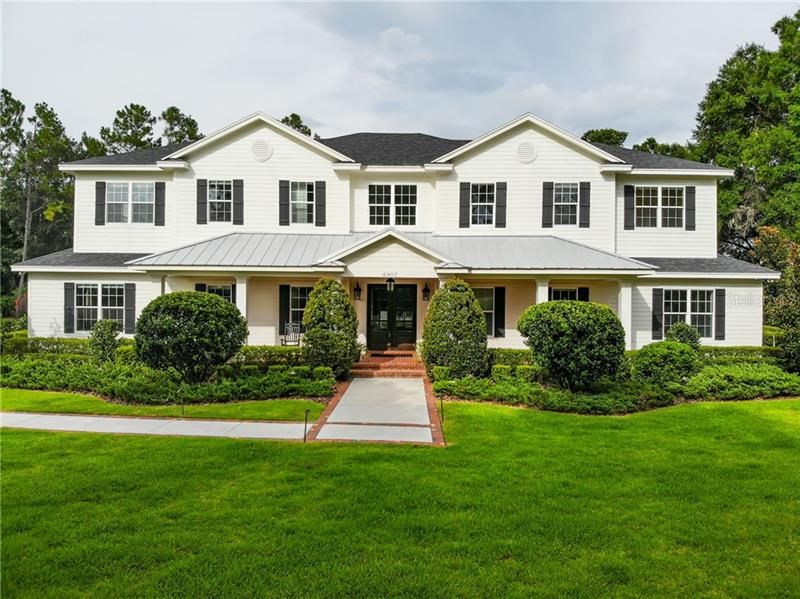 EXTERIOR FRONT VIEW WITH LUSH LANDSCAPING AND EXPANSIVE FRONT PORCH