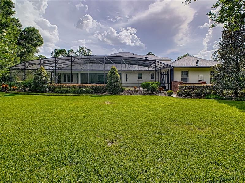 REAR EXTERIOR VIEW WITH THE EXPANSIVE BACK YARD. BEAUTIFUL LANDSCAPING ON THIS 1.5 ACRE LOT