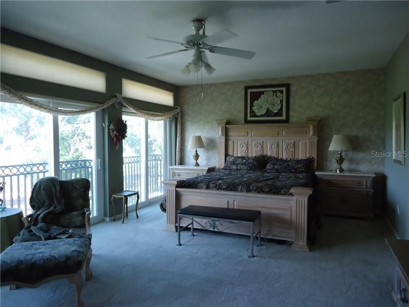 Master bedroom with king bed with three sliders with the blinds open