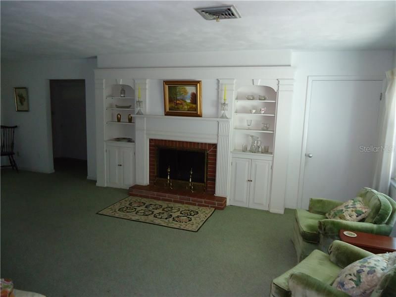 fireplace with built in shelving (door to right is storage, door opening to left to enter bedrooms)